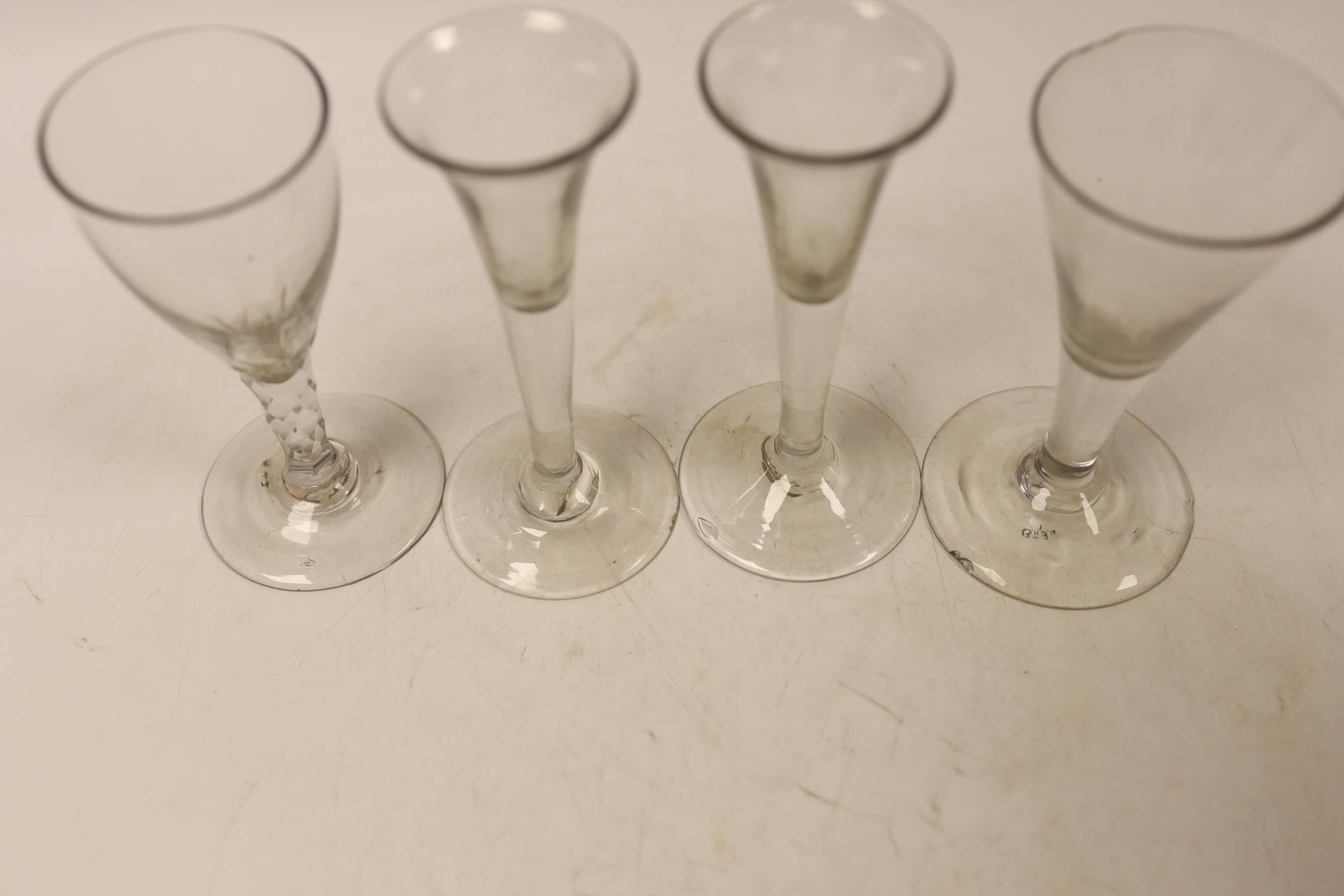 Three mid-18th century drawn trumpet drinking glasses, and a facet stem glass, tallest 13cm (4)